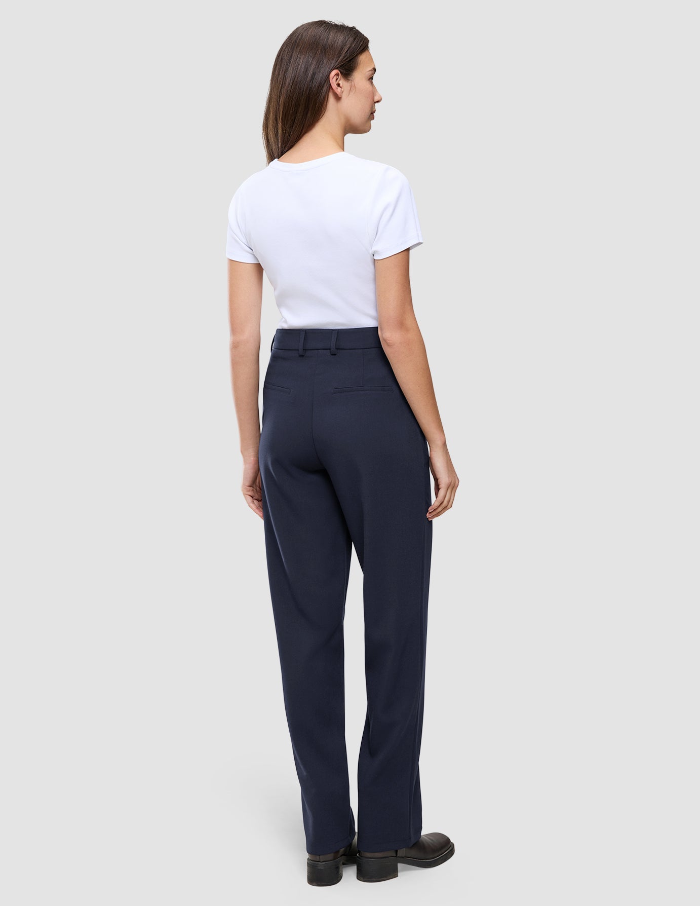En kvinna bär en vit t-shirt och byxorna Women GO2 Pants Straight Blue Nights, som har raka ben och en skandinavisk design.